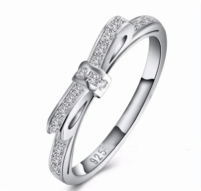 Silver couple ring with a bow shape set with rhinestones and zircon crystals.
