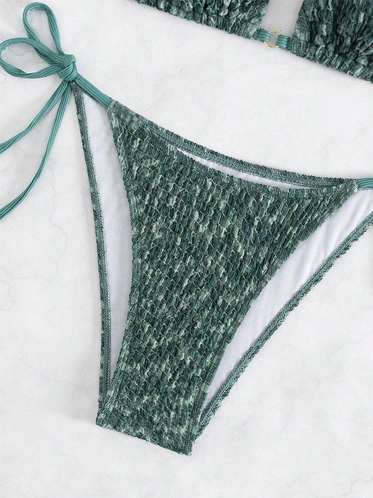 Green backless halter swimsuit with adjustable straps and matching shorts on mannequin