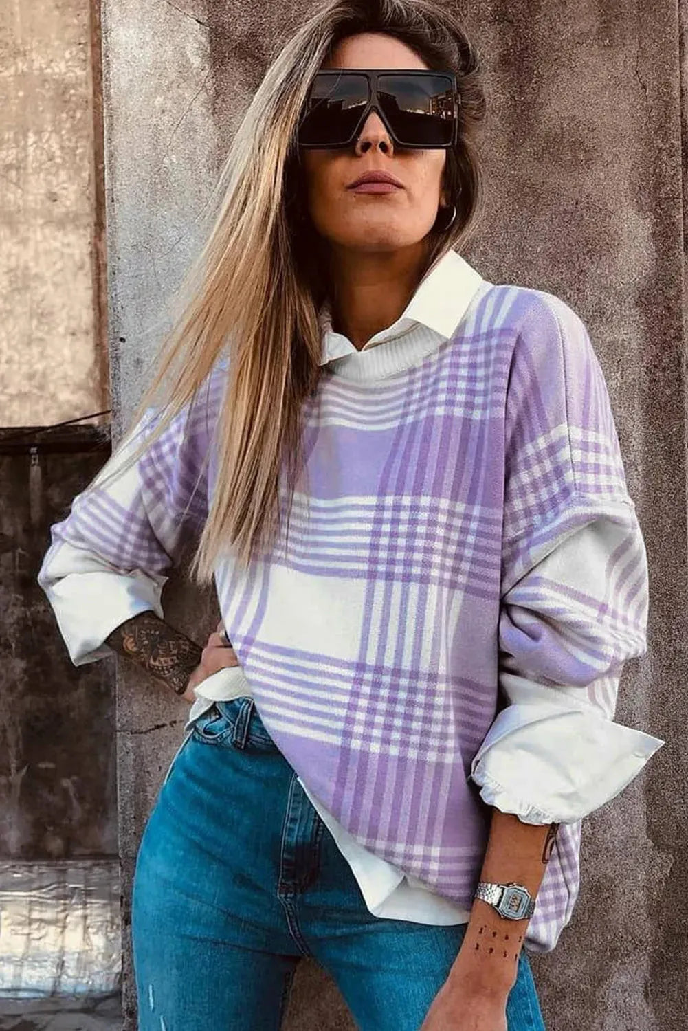 Loose lilac plaid print sweater with ribbed trim and long sleeves on a hanger.