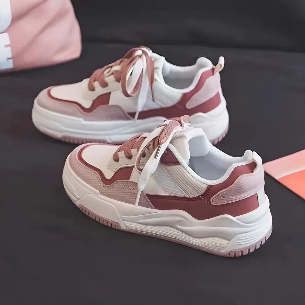 Pink and white low top women's sneakers with a rubber sole and height increasing feature.