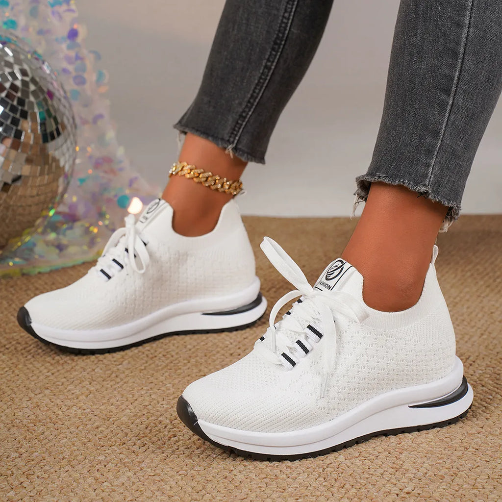 Women's black and white lace-up sneakers with mesh upper and flat rubber sole on a white background.