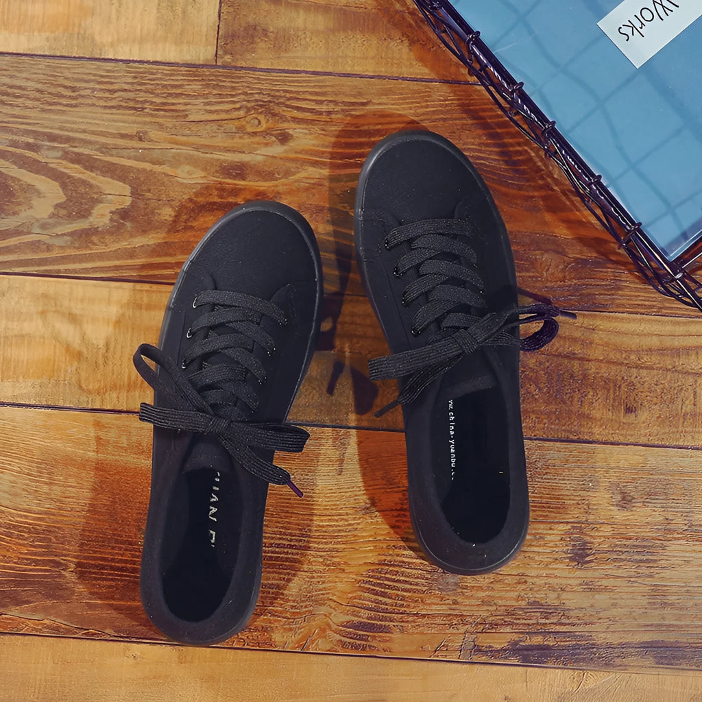 All-black low-top women's canvas shoes with flat rubber sole and lace-up front