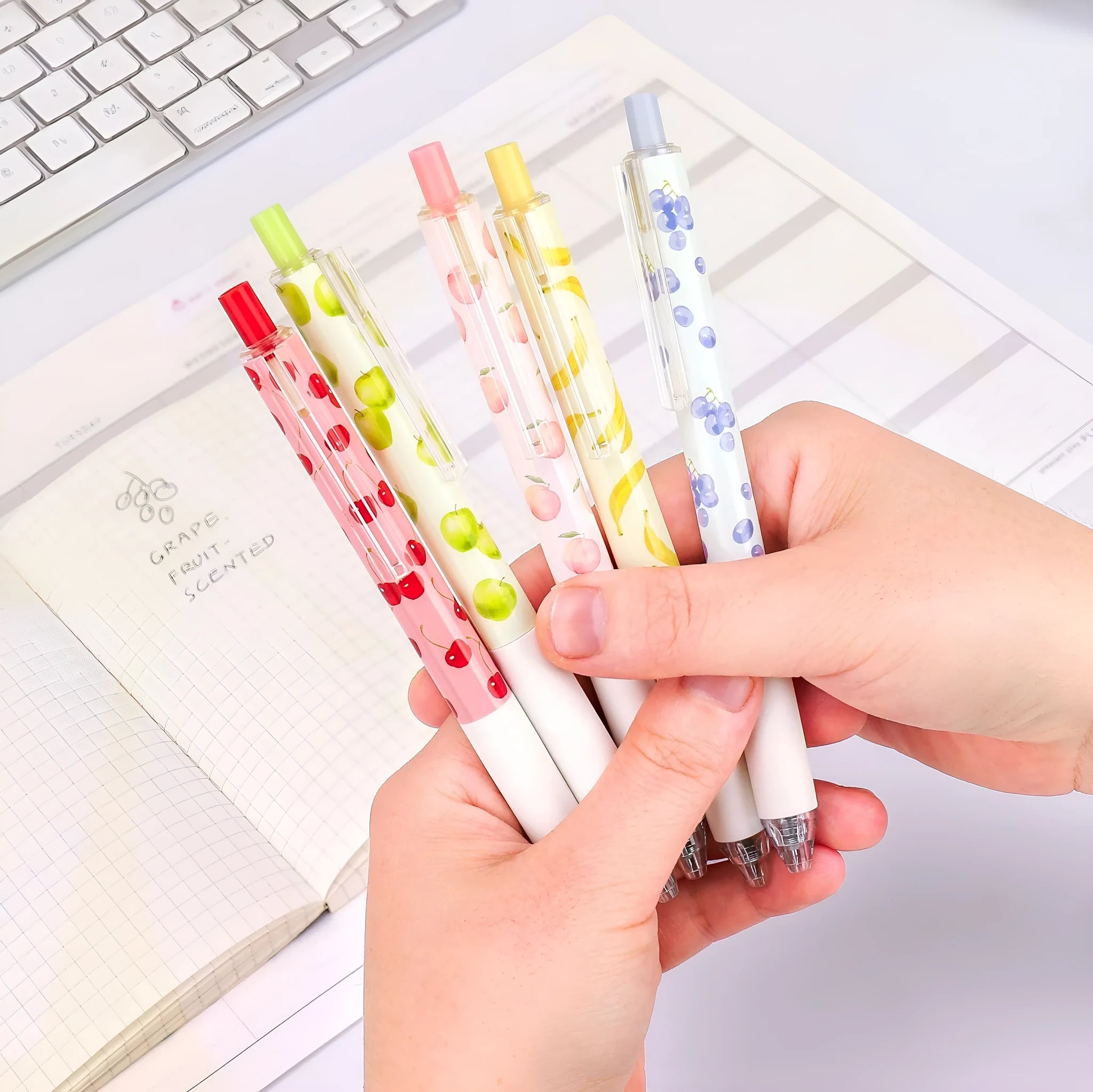 Three scented fruit ballpoint pens with press-action mechanism showing extended writing tips