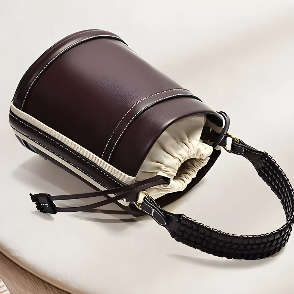 Brown PU cylindrical tote bag with dual handles and woven decorative stitching lines.