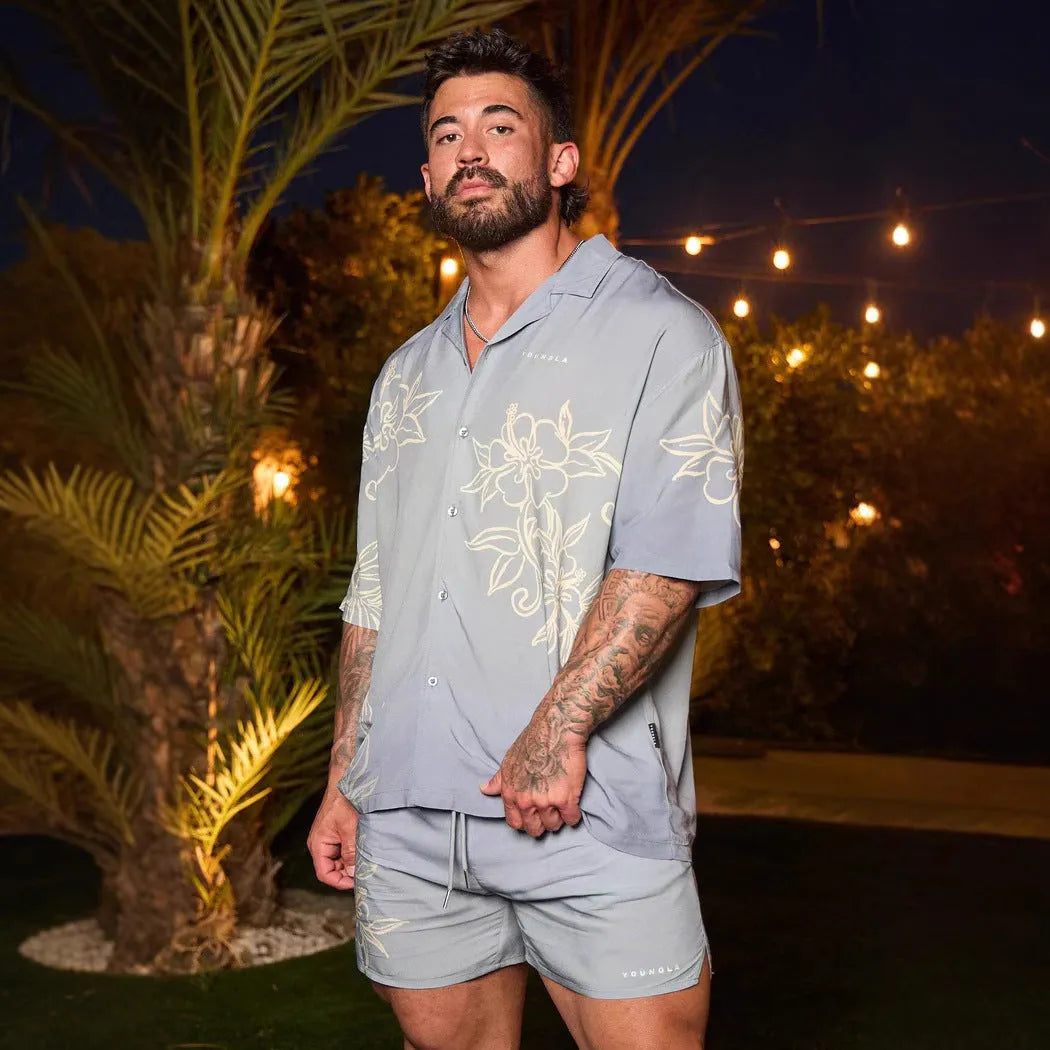 Man wearing a loose-fitting grey short-sleeve top with a floral print design.