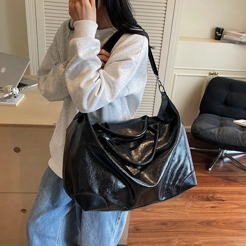 Women's hand-carry travel bag in black or silver with 36-55 litre capacity and PU material construction
