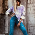 Loose lilac plaid print sweater with ribbed trim and long sleeves on a hanger.