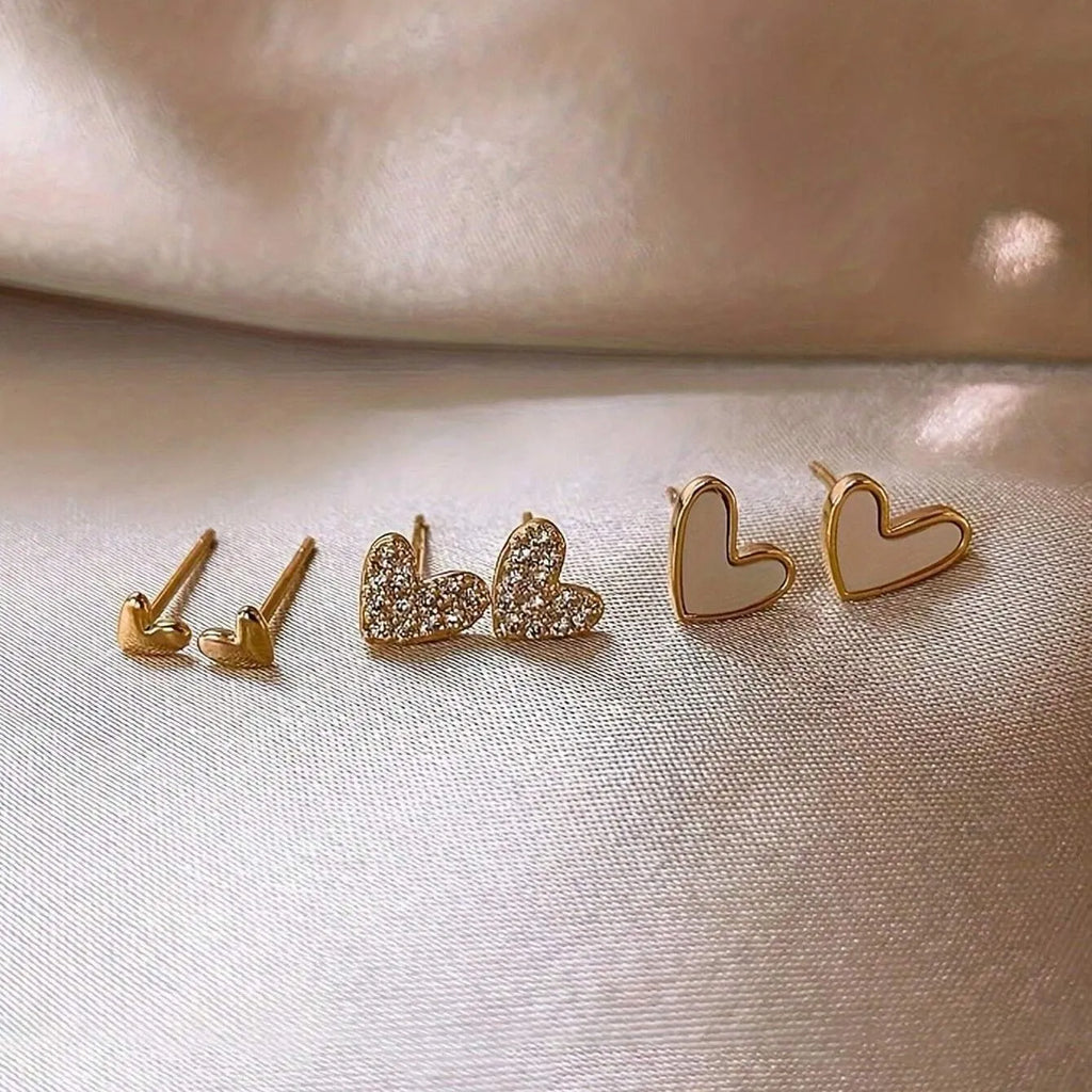 Three pairs of women's alloy heart-shaped earrings in gold, black, black-white, and pink colours
