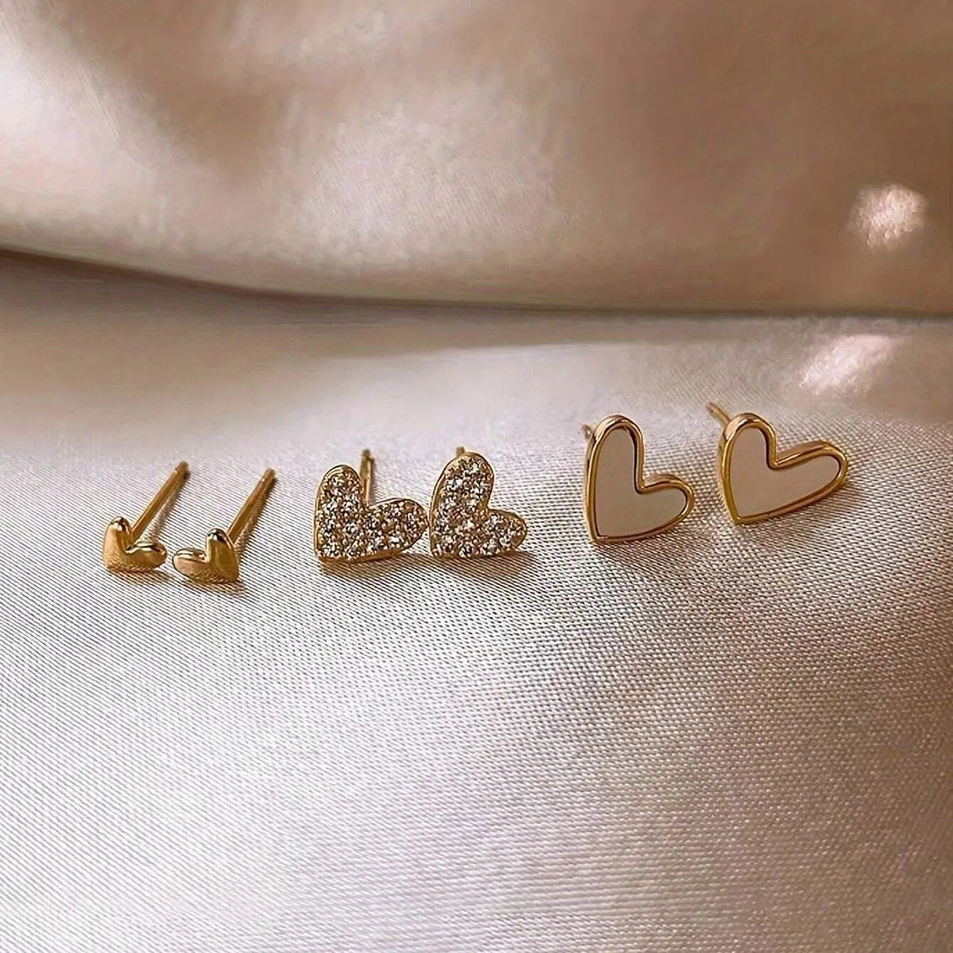 Three pairs of women's alloy heart-shaped earrings in gold, black, black-white, and pink colours