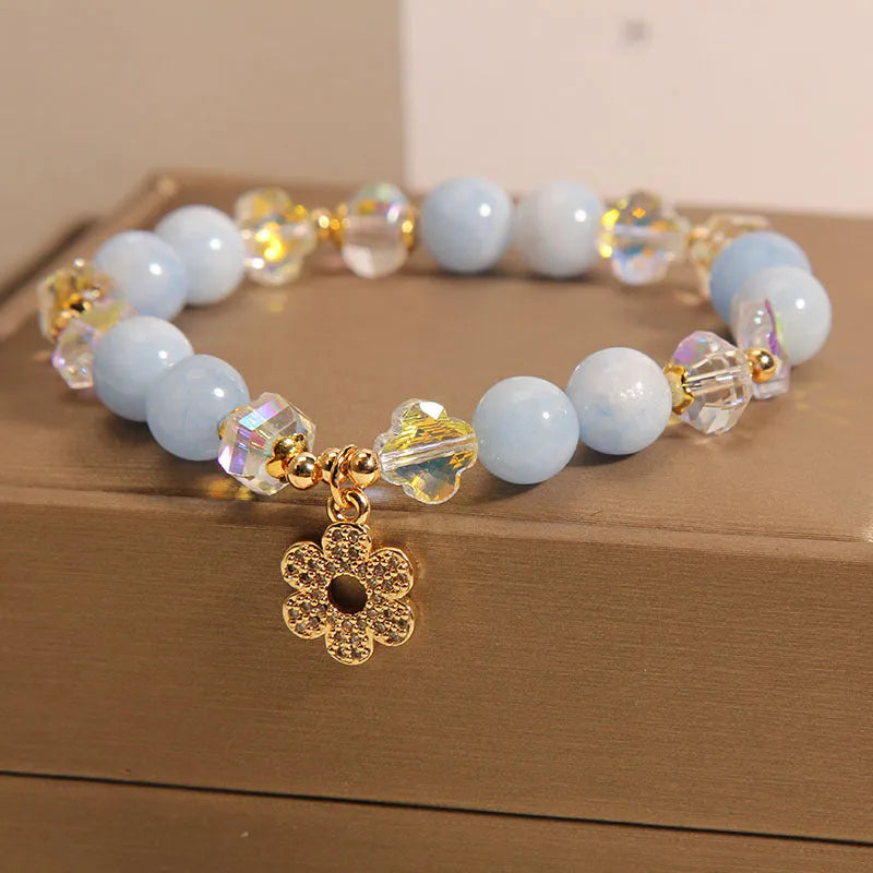 Women's aquamarine crystal bracelet with a four-leaf clover charm and small pearl accent.