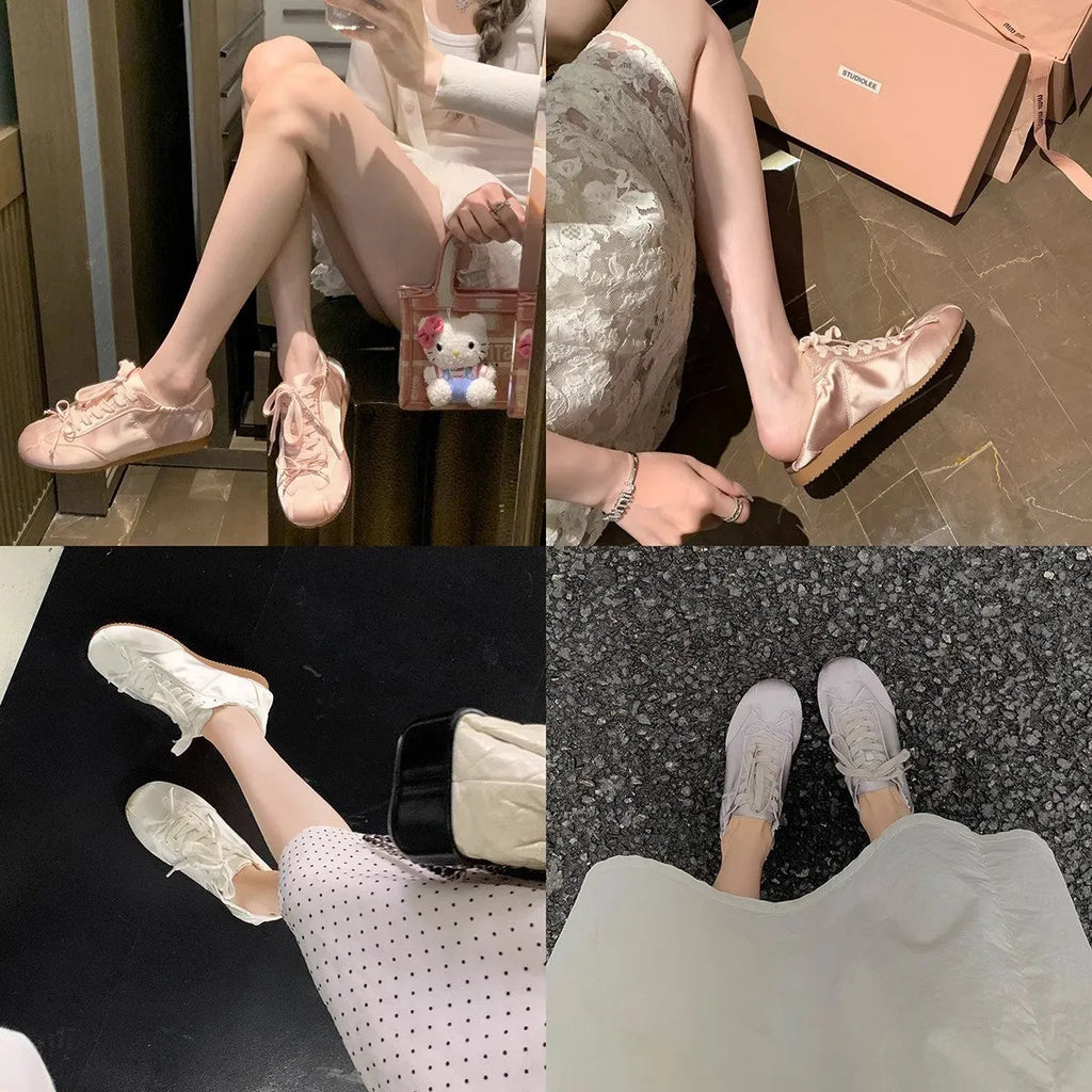 Women's silver grey satin ballet flats with round toe and white lace-up front on a plain background.
