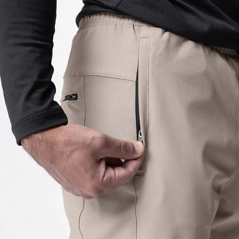Men's loose grey fitness trousers with elasticated ankle ties on a gym floor.