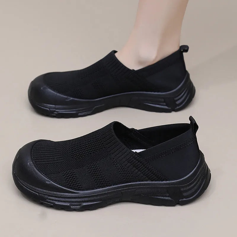 Women's black oversleeve shoes with round toe and soft flat PVC sole.