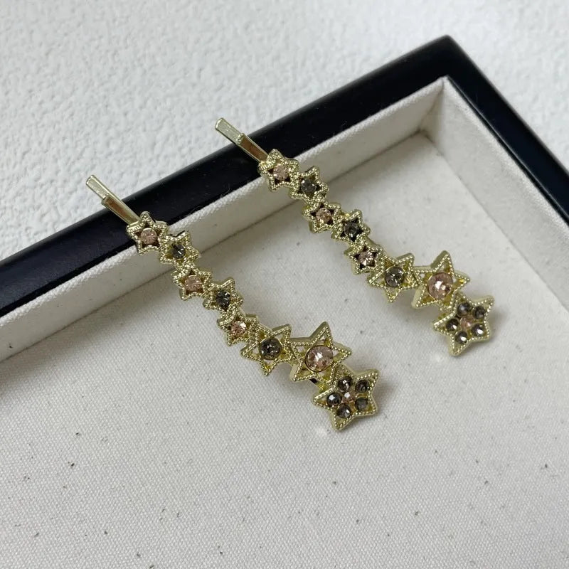 Gold alloy rhinestone barrette with a side clip, star decoration, and text.