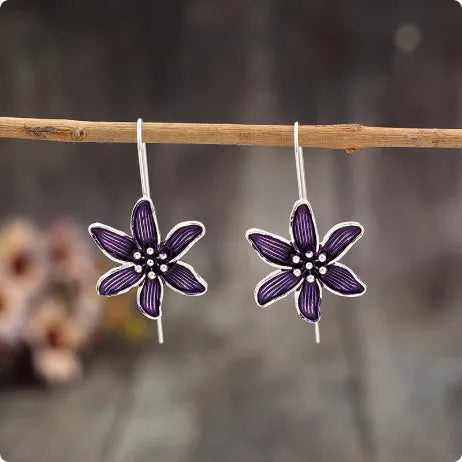 A pair of retro-style purple flower-shaped alloy earrings for women on a plain background.