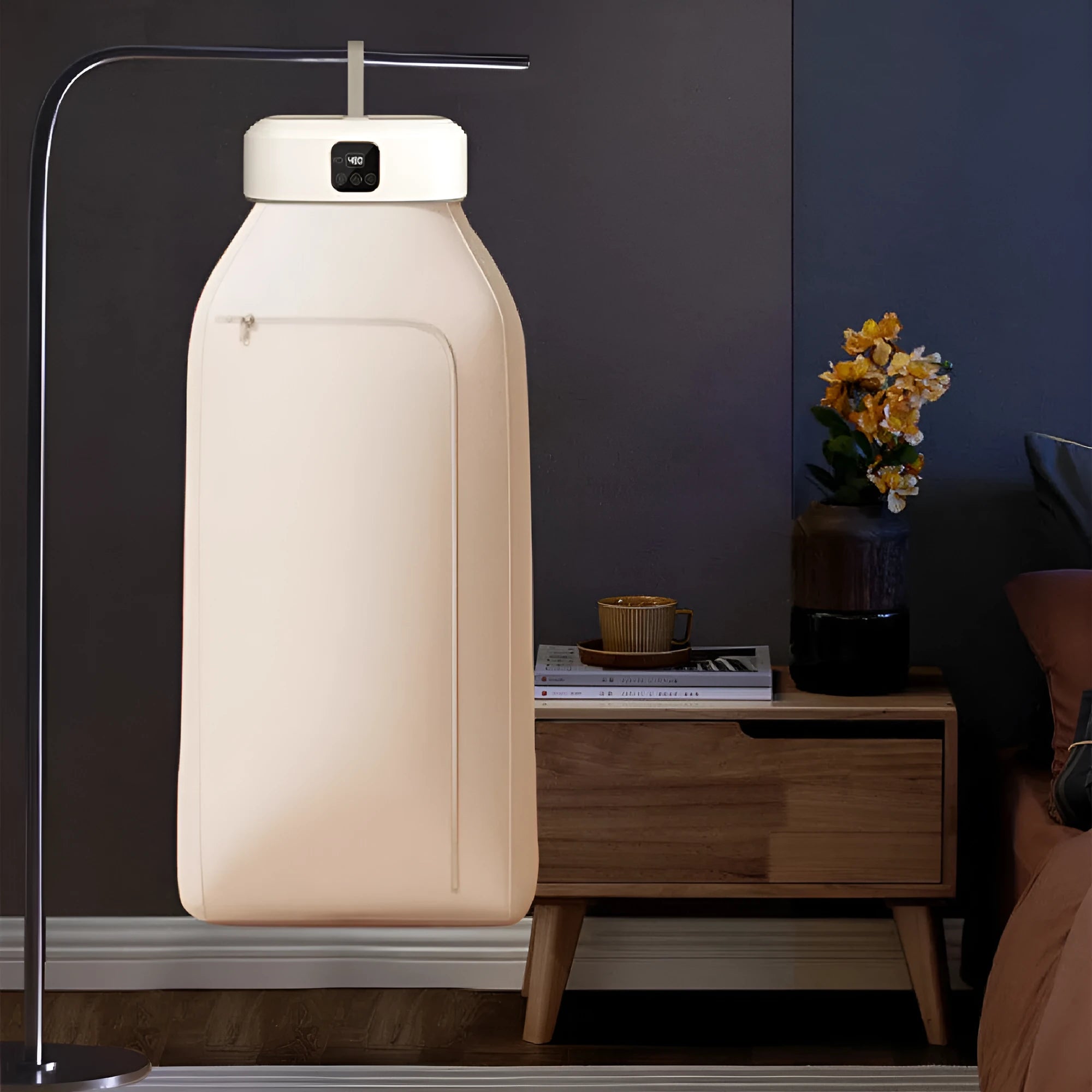 White cylindrical foldable clothes drier with remote control on a table.