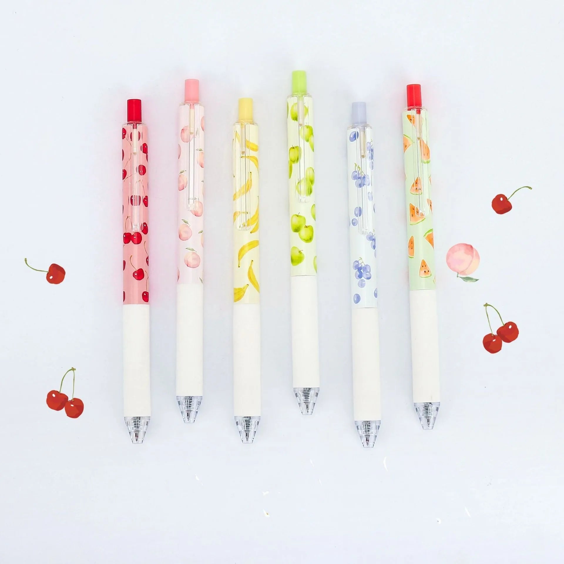 Three scented fruit ballpoint pens with press-action mechanism showing extended writing tips