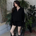 Creamy-white cable knit jumper and shorts set on a hanger, showing geometric pattern and elastic waist.