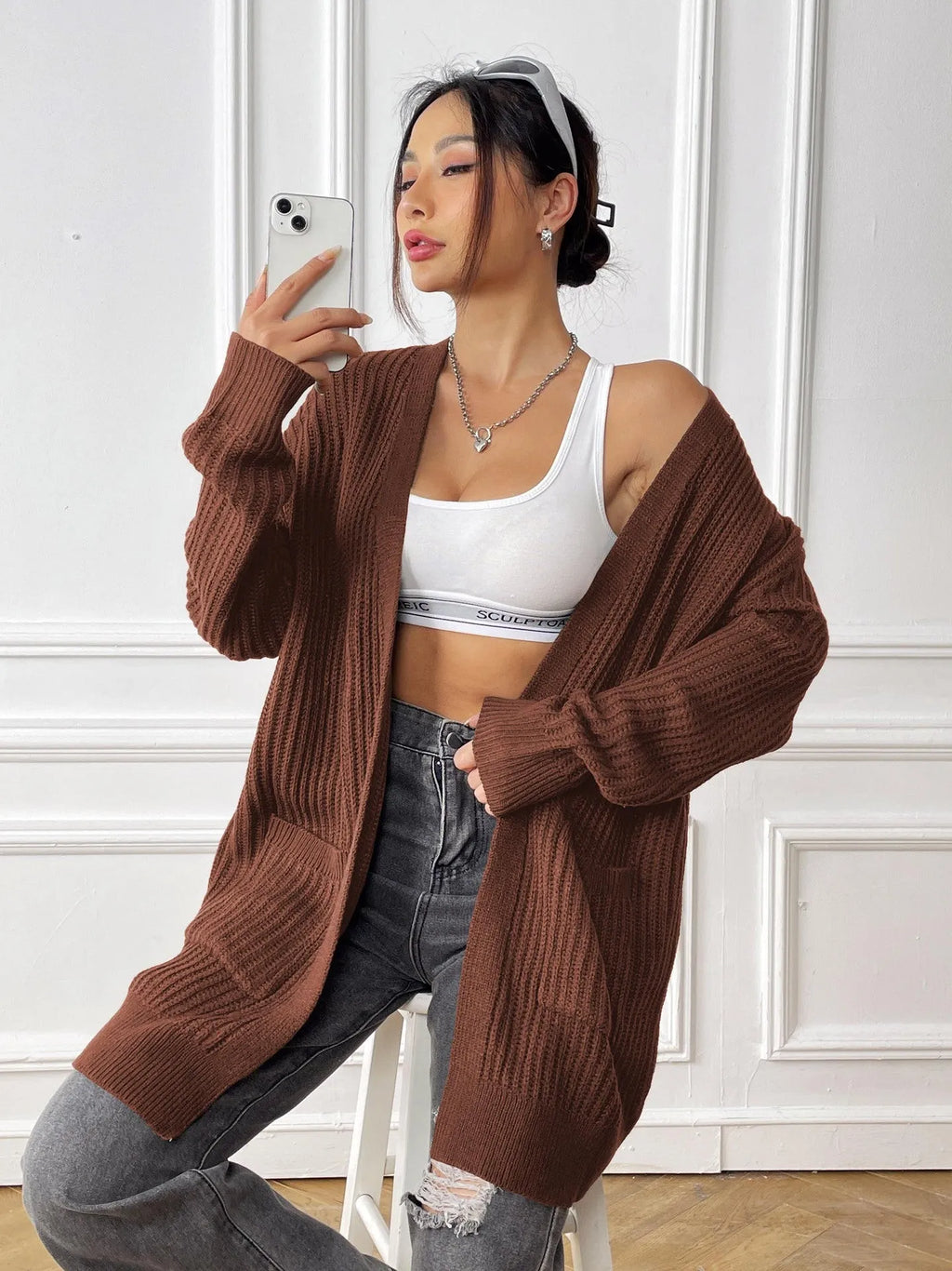 Women's dark green loose-fit acrylic cardigan sweater with double pockets and long sleeves.