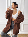 Women's dark green loose-fit acrylic cardigan sweater with double pockets and long sleeves.