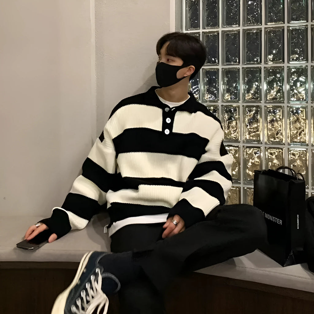 Man modelling a loose fit black and grey striped polyester sweater coat, long sleeve pullover style.