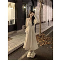 Women's milky white V-neck knitted long dress with princess sleeves on a hanger.
