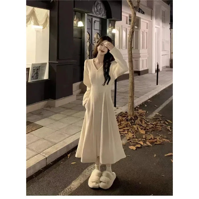 Women's milky white V-neck knitted long dress with princess sleeves on a hanger.