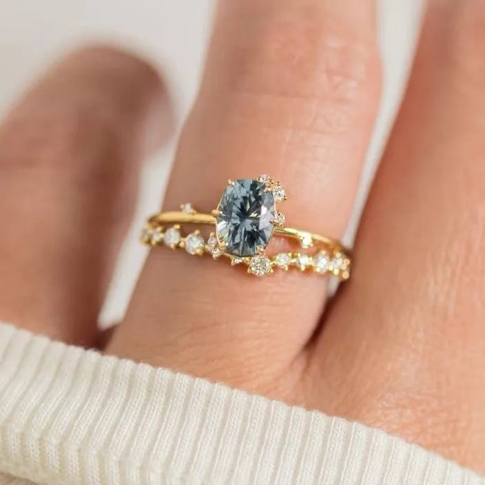 A pair of gold-plated floral rings with a central green zircon stone on a white background.