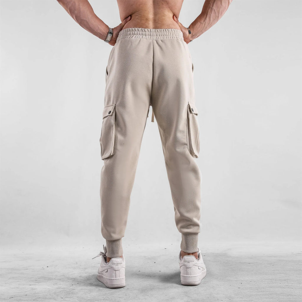 Men's loose-fit cotton sports trousers with ankle-tied cuffs and multiple pockets in a light grey colour.