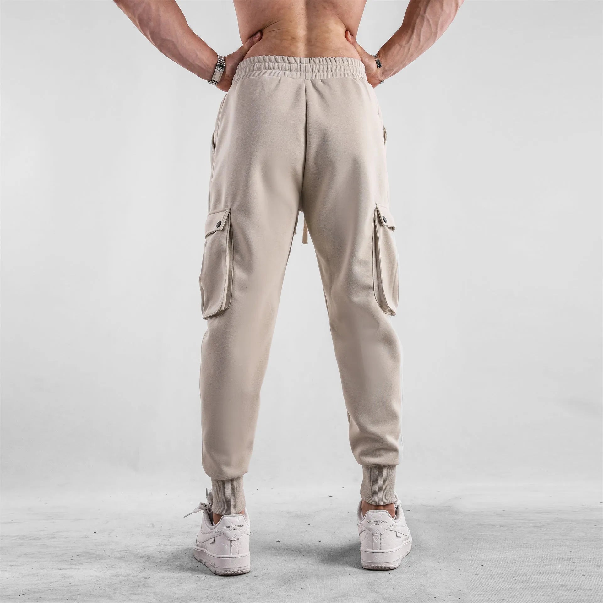 Men's loose-fit cotton sports trousers with ankle-tied cuffs and multiple pockets in a light grey colour.
