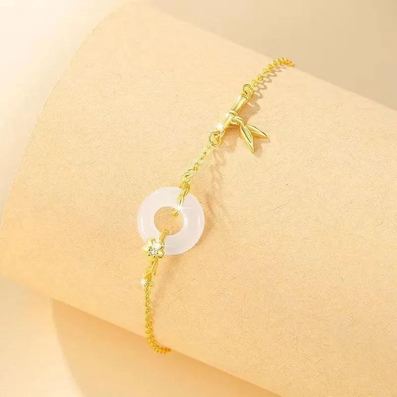 Gold-coloured women's silver bracelet with a peace buckle design and white chalcedony stone centrepiece.