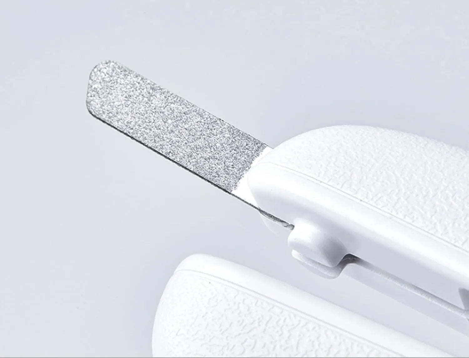 White pet nail clippers with LED light, transparent guard, and nail file on a grey background.