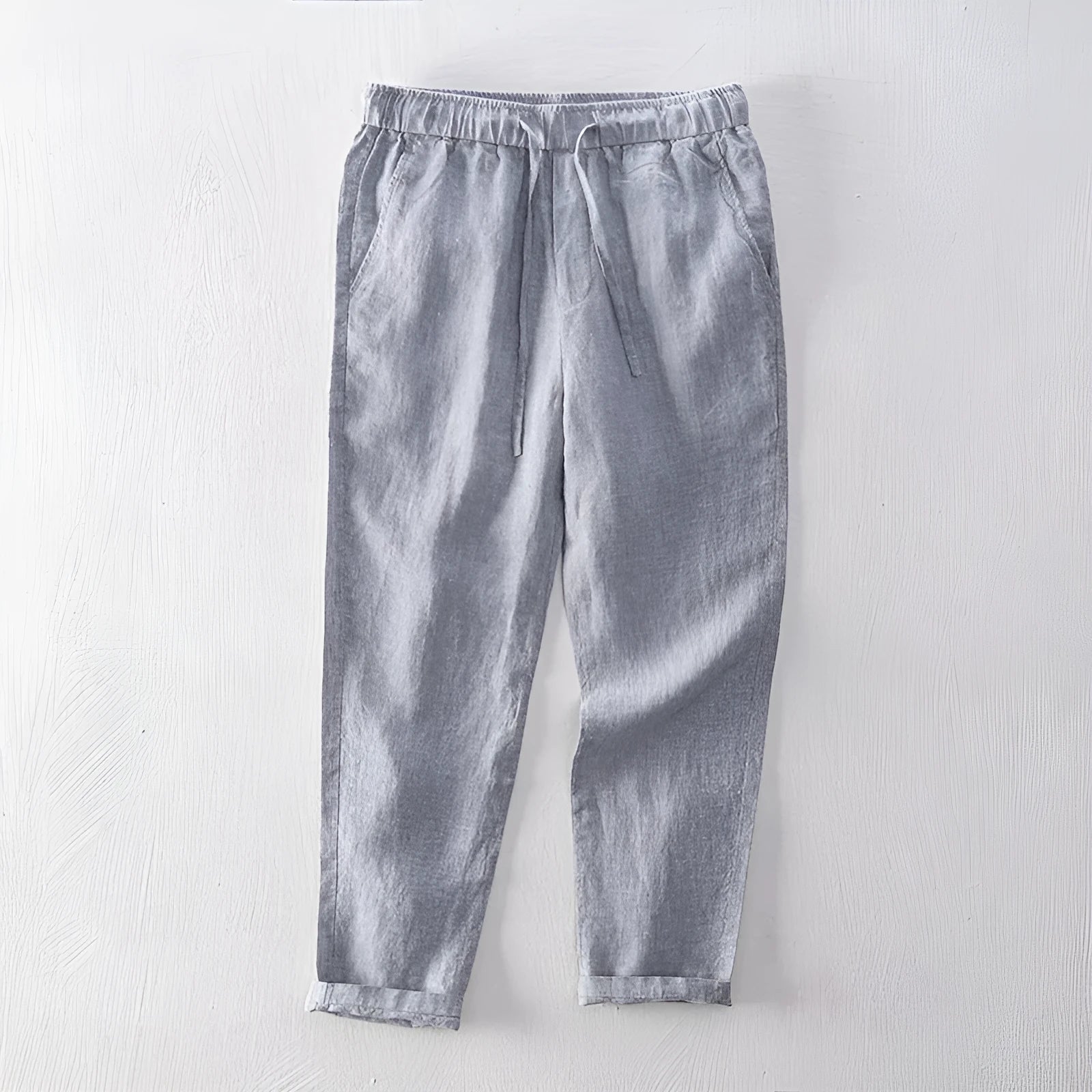 Men's straight-leg linen trousers in dark grey laid flat, showing mid waist and relaxed fit