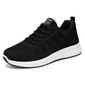 Women's black flyknit casual running shoes with white soft sole and flat heel on a grey background.