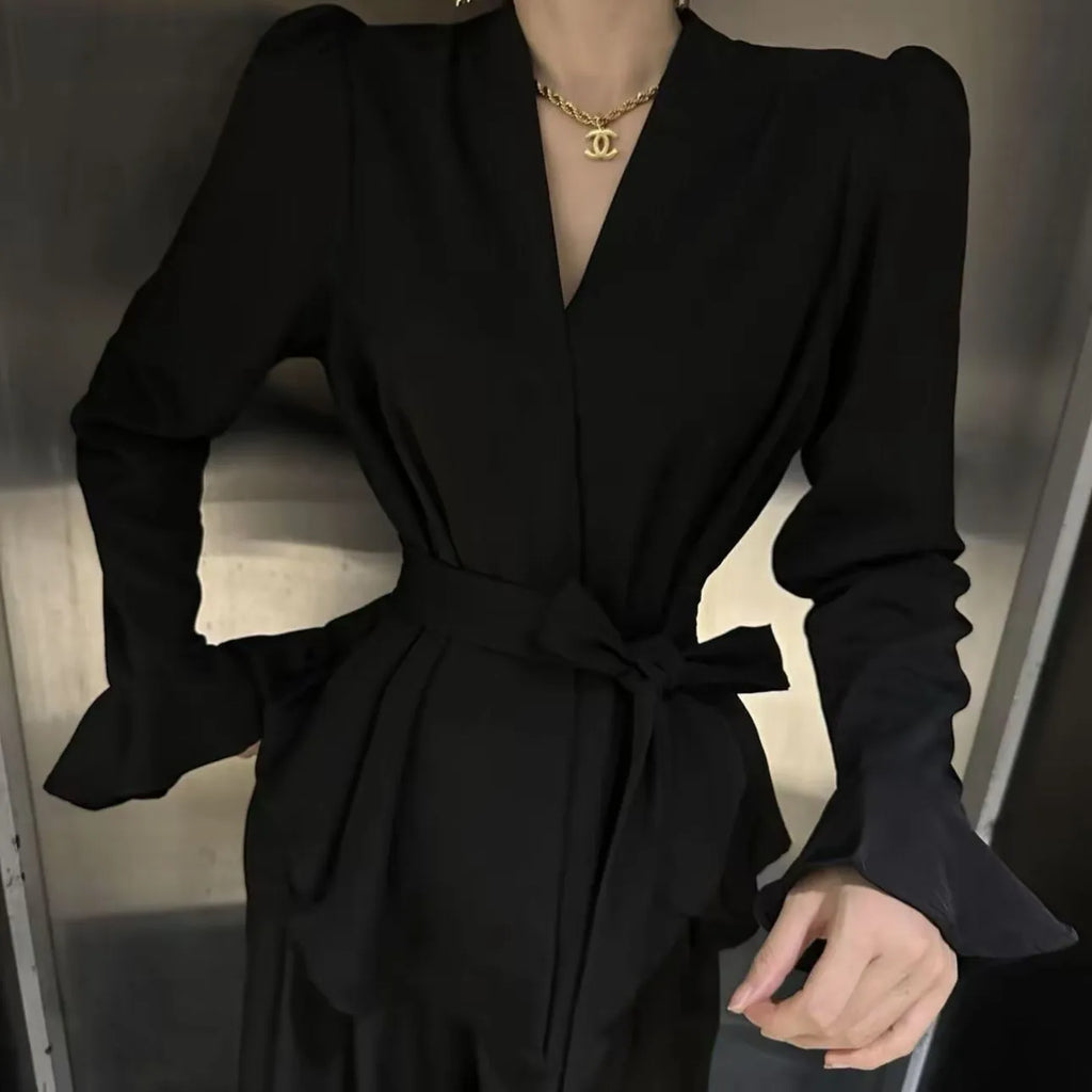 Women's black French-style shirt with an irregular collar and long bell sleeves laid flat.