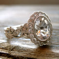 A geometric copper ring for women with a white gold coloured plating and a round zircon stone, shown on a finger.