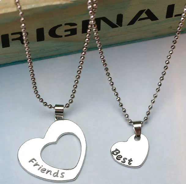 Two matching silver heart-shaped cross chain necklaces on a surface, alloy construction