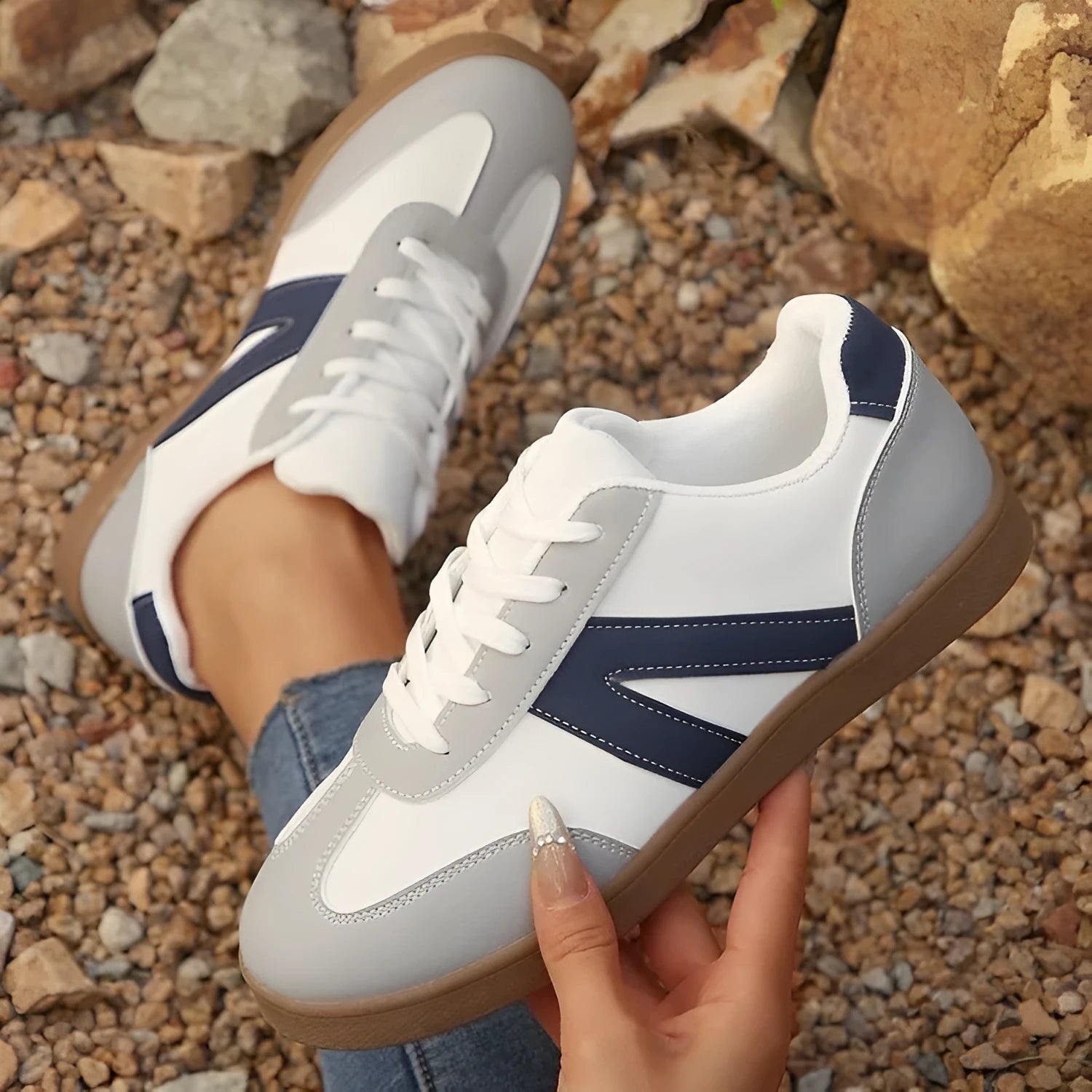 Blue women's low-top hiking shoes with rubber sole and lace-up design on an outdoor background.