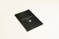 Black A5 hardcover dream journal with gold lettering, shown open on a lined page with a silk ribbon bookmark.