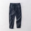 Men's straight-leg linen trousers in dark grey laid flat, showing mid waist and relaxed fit