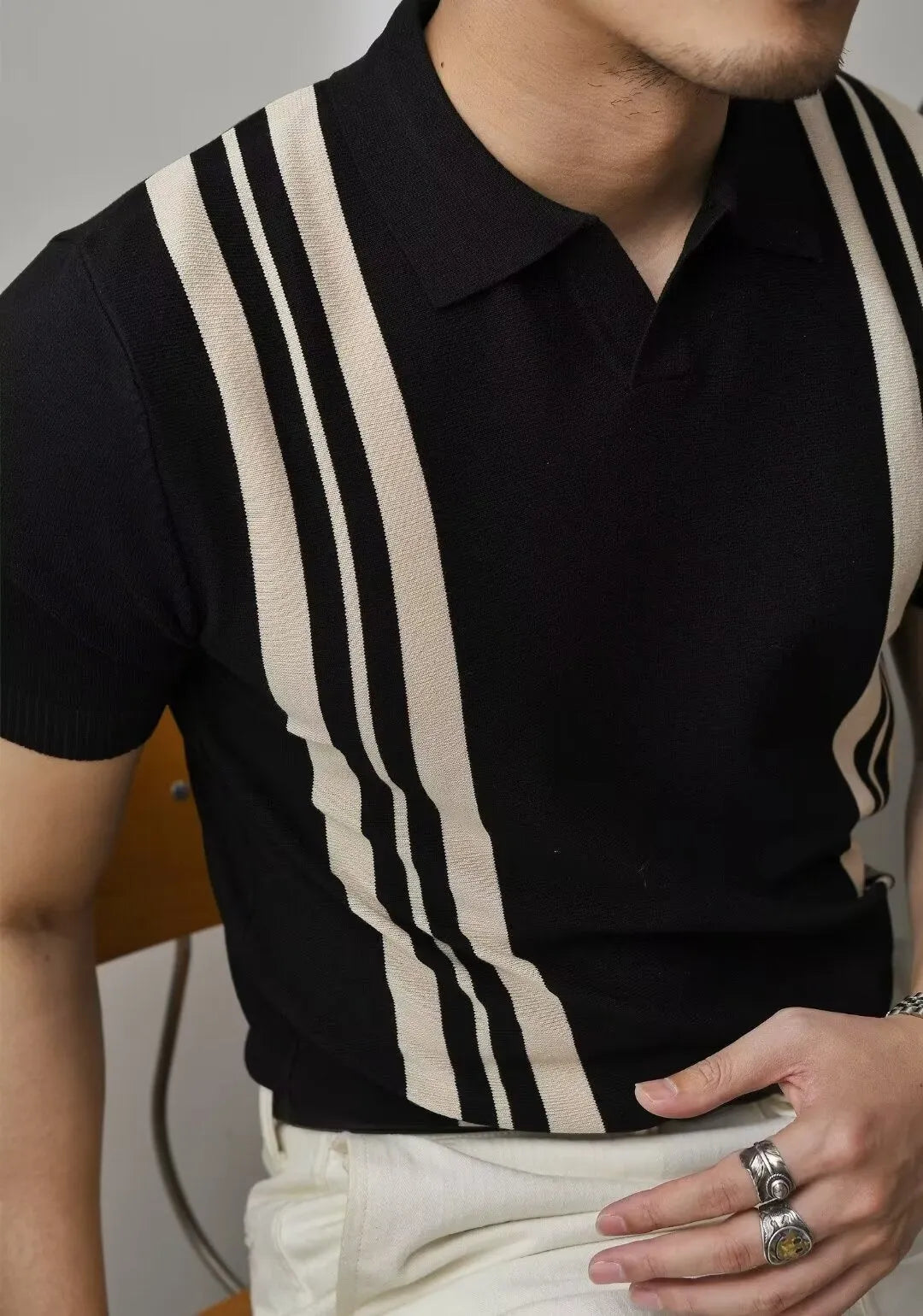 Men's black polo shirt with knitted collar and short sleeves laid flat.