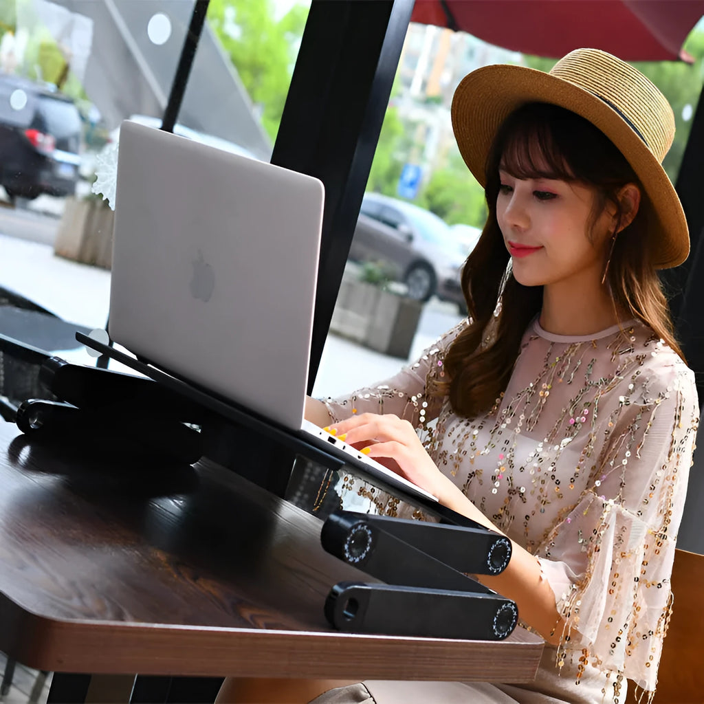 Black folding metal bed desk with cooling fan and laptop placed on it.