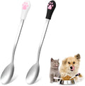 Two stainless steel pet food spoons with white and black silicone handles featuring a cat paw print design.