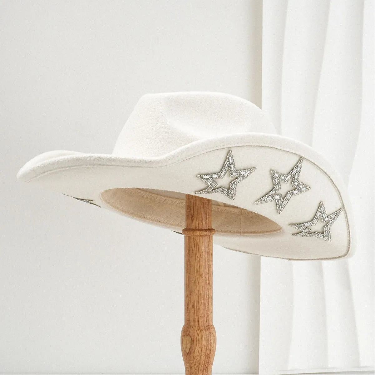 Beige woolen felt Western-style top hat with a conical crown and a silver hexagonal star decoration on the front.
