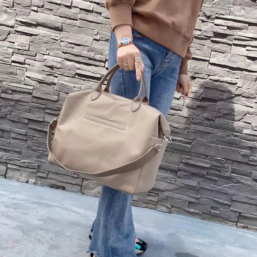 Black nylon waterproof shoulder bag with leather trim showing large main compartment