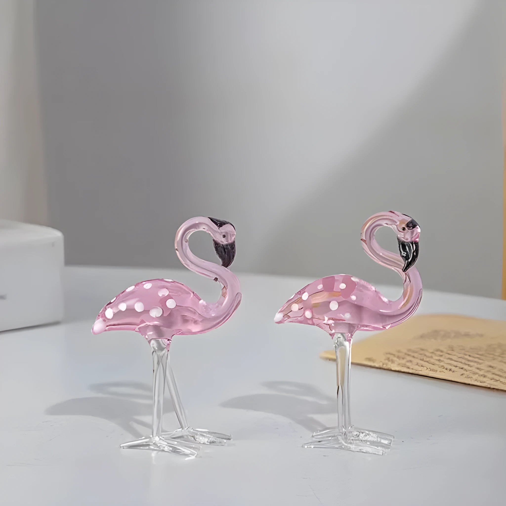 A pink flamingo decorative ornament made from clear white crystal on a table.
