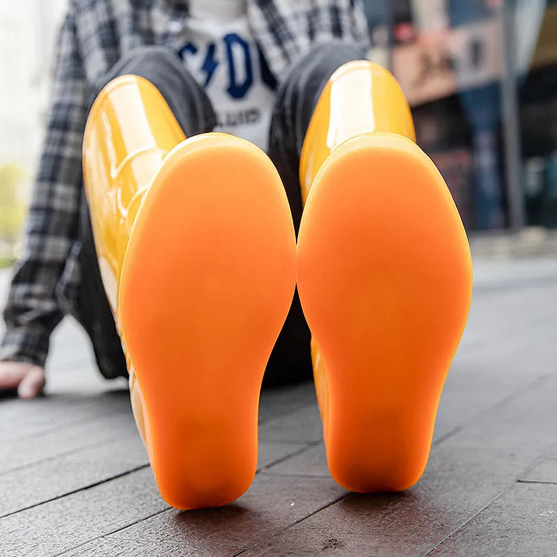 White and yellow high tube plastic rain boots with flat heel and round toe.
