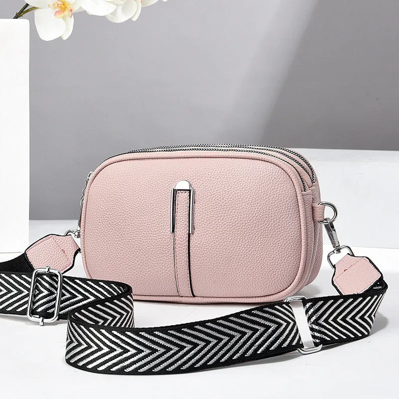 A soft oval-shaped women's crossbody bag in PU leather with a stone pattern texture and a front slit pocket.