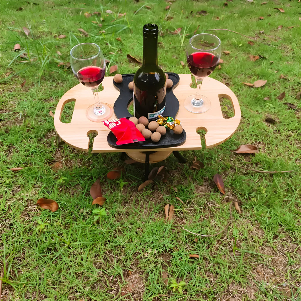 Creative multifunctional white wood wine glass rack tray with bottle holder handle holding four wine glasses and a bottle on a picnic table