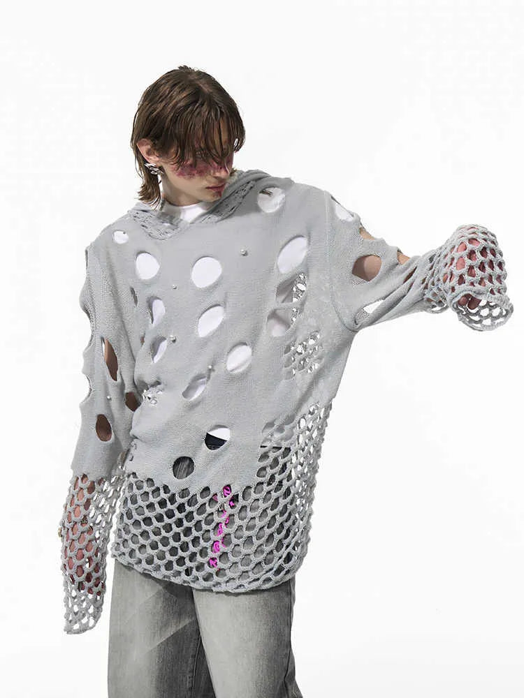 Man wearing a black loose-fit hollow knit hoodie with pearl decorations on the hood.
